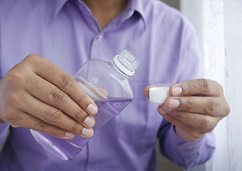 Person pouring purple mouthwash into a cap